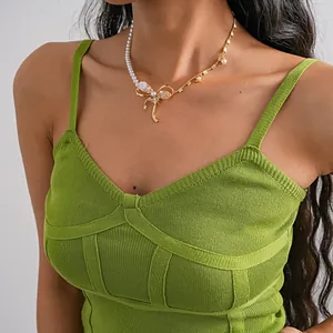 Detail view of pearl and gold bow necklace with bee and flower accents on a model