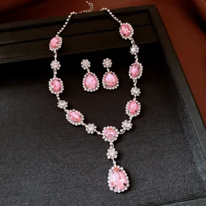 Detailed view of pink teardrop gemstone necklace and earring set with rhinestone halo.
