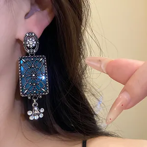 Dettaglio di orecchini a sospensione quadrati stile vintage con smalto blu e strass brillanti