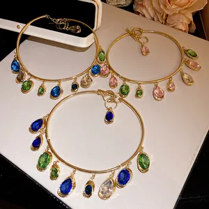 Gros plan de colliers ras du cou dorés avec pendentifs en pierres précieuses colorées.