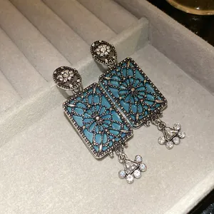 Dettaglio ravvicinato di orecchini vintage quadrati con filigrana e smalto blu chiaro