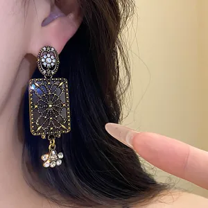 Dettaglio di orecchini pendenti vintage in stile corte con strass brillanti