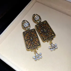 Dettaglio di orecchini vintage rettangolari con strass brillanti e motivi intricati