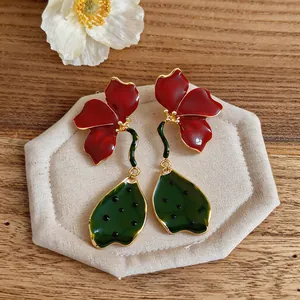 Vue détaillée de boucles d'oreilles fleurs en émail rouge et vert, design plissé 3D