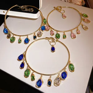 Détail de pendentifs en pierres colorées sur des colliers dorés avec fermoir OT