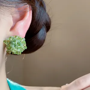 Detalle de primer plano de un pendiente de botón de flor de cristal verde con aguja de plata