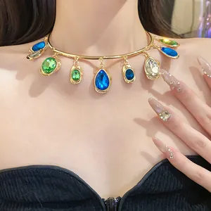 Détail d'un ras-du-cou doré orné de strass colorés en forme de larme et d'ovale.