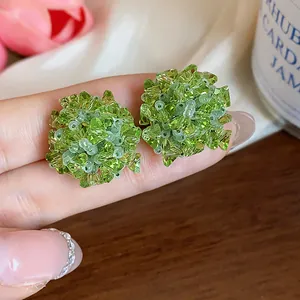 Primer plano detallado de pendientes de flores de cristal verde con cuentas de cristal