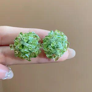 Detalle de los elegantes pendientes de flor en cristal verde de estilo forestal