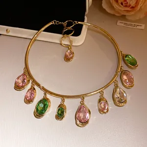 Gros plan sur le collier ras du cou doré avec des pendentifs en cristal rose et vert vif.