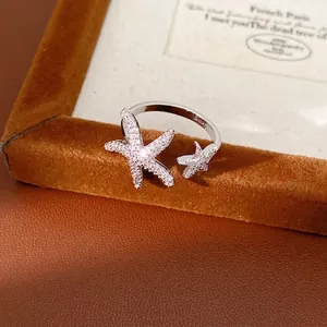 Elegant silver starfish open ring with sparkling zircon stones on a brown velvet stand
