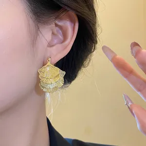 Elegante goldene Ginkgoblatt-Ohrringe mit Fransen, von einem Model getragen