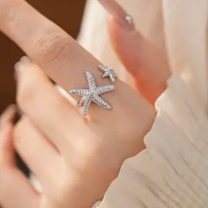 Close-up macro view of a silver-colored starfish open ring with sparkling micro-pave zircons.