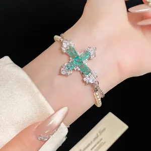 Luxurious emerald green cross pendant bracelet with white zircons and pearls on wrist