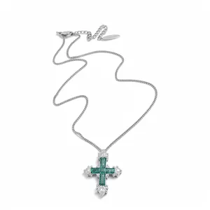 Elegant silver cross necklace with emerald green zircons on a clean white background.