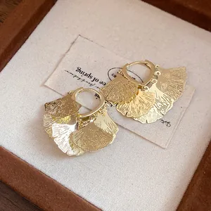 Detailansicht der Vintage Gold Ginkgo Blatt Quasten Creolen auf einem Display.