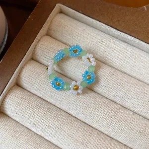 Détail d'une bague fleur artisanale en perles de verre avec pétales bleus et blancs
