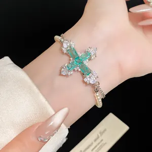 Detailed macro view of a green zircon cross bracelet featuring white pearl strap.