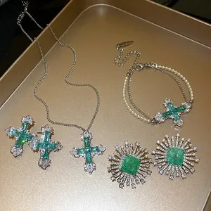Detailed view of luxury emerald zircon cross necklace and sunburst stud earrings set