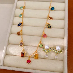 Primo piano di collana placcata oro 18k con zirconi colorati e orecchini di perle.