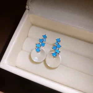 Elegant silver stud earrings with blue stones and round white resin pendants in box