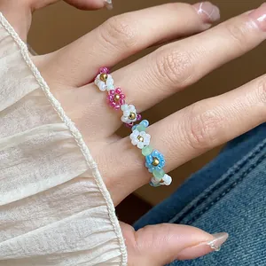Détail d'une bague fleur en perles de verre colorées faite à la main sur un doigt
