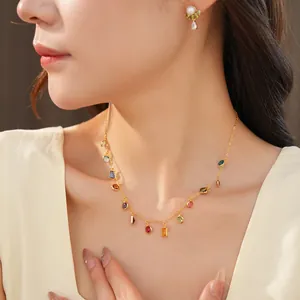 Primo piano di una collana placcata oro 18k con pendenti in zirconia colorata su modella.