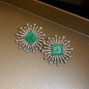 Macro view of luxury sunburst stud earrings featuring a brilliant square green stone
