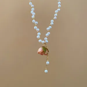 Dettaglio ravvicinato di elegante collana di perle con ciondolo a rosa stabilizzata rosa