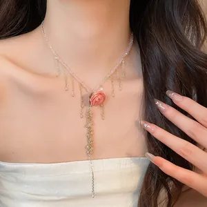 Dettaglio della collana con pendente rosa eterna e catene di nappe dorate su modella