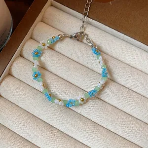 Gros plan détaillé d'un bracelet fleuri en perles fait main avec des touches bleues et blanches.
