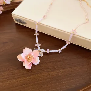 Dettaglio ravvicinato di un romantico ciondolo a rosa rosa su una collana di perline dorate