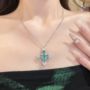 Close-up detail of an elegant cyan zircon cross pendant necklace worn on model's neck.