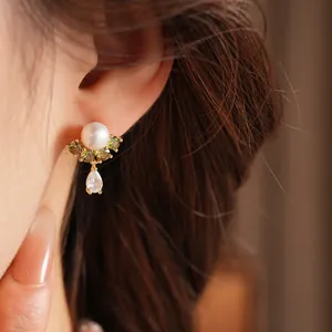 Dettaglio elegante orecchino di perle placcato oro 18k con zirconi verde oliva e chiari