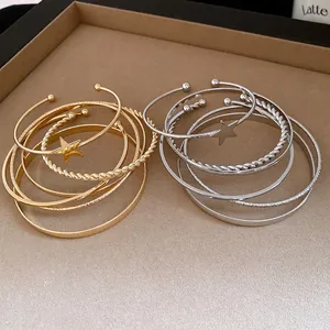 Elegant close-up of retro gold and silver star open bangles on a beige display tray