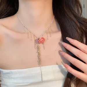 Dettaglio di una collana con pendente a rosa rosa, catena di perle e nappe eleganti