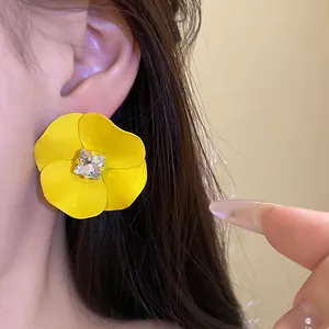 Primer plano detallado de un pendiente de flor amarilla con un brillante de cristal