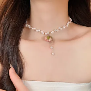 Primo piano di un ciondolo con rosa vera su una collana di perle elegante indossata da una modella