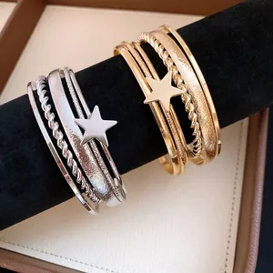 Close-up of retro star open bangles in gold and silver finish with various textures.