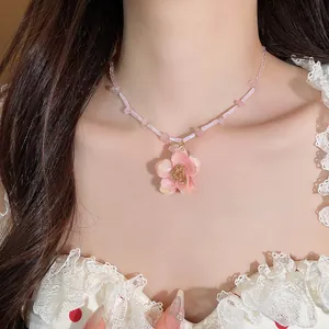 Primo piano di una collana con pendente a fiore rosa indossata da una modella in pizzo