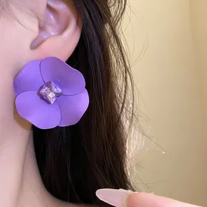 Primer plano de un pendiente de flor pintada de morado con un cristal central brillante