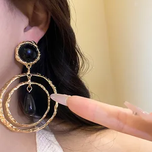 Elegant oversized gold hammered hoop earrings featuring black resin teardrop pendants for women