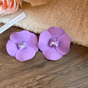 Detalle de elegantes pendientes de flores moradas con un cristal violeta central