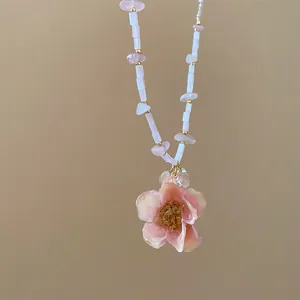 Vista dettagliata di una collana con ciondolo a fiore rosa e perle eleganti