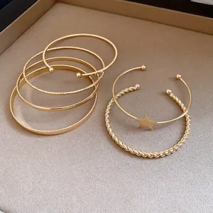 Macro view of a 6-piece gold-toned bracelet set featuring a star charm and twisted textures