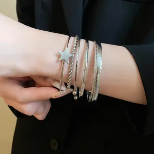 Close-up detail of multi-layered silver star open bangles worn with a chic black blazer