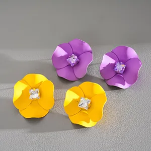 Close-up of matte spray-painted floral stud earrings with square rhinestone centers