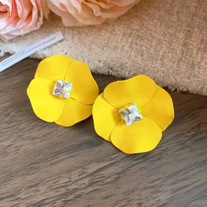 Primer plano de pendientes de flores amarillas con un cristal cuadrado sobre mesa de madera