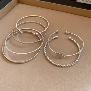 Close-up view of silver-toned retro bangle set featuring star charm and twisted cuff designs.