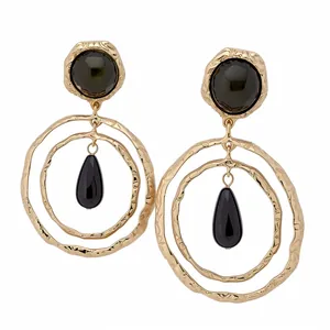 Vintage style gold crumpled metal hoop earrings featuring black teardrop resin pendants
